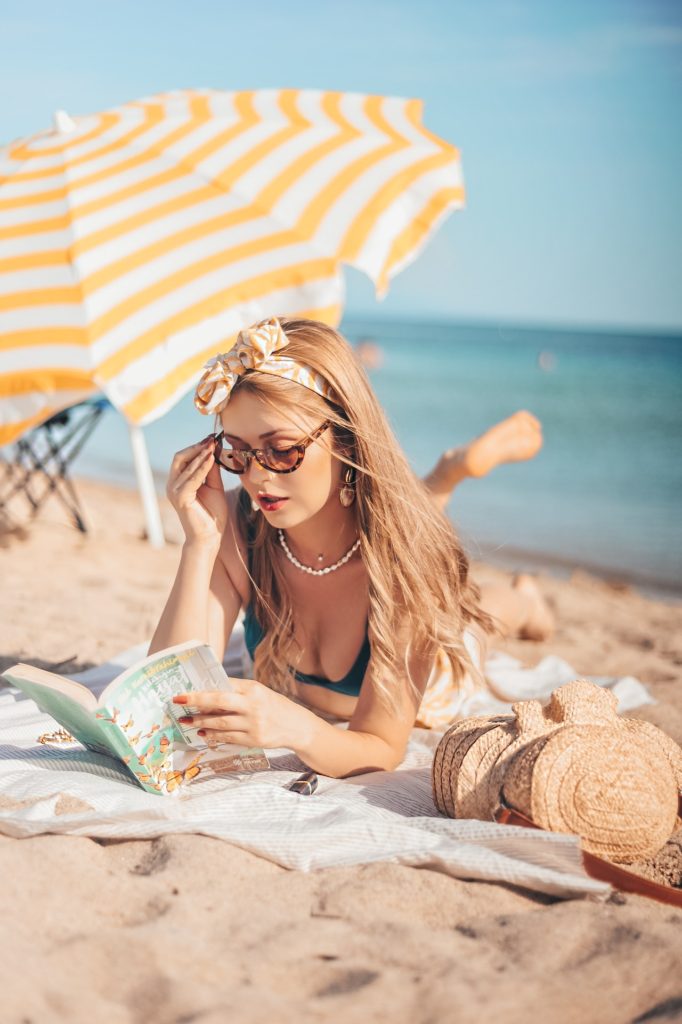 women-s-lying-on-the-beach-sand-reading-a-book-3087898