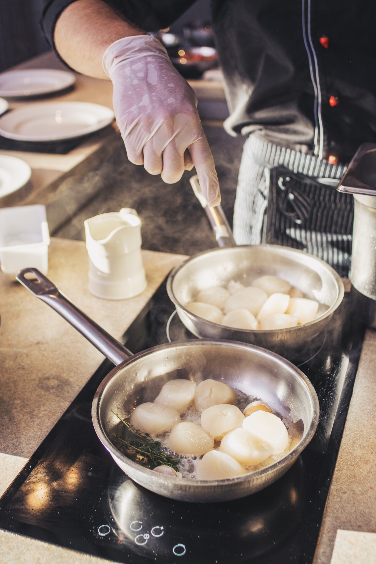 photo of person with vinyl gloves holding stainless steel pot on stove