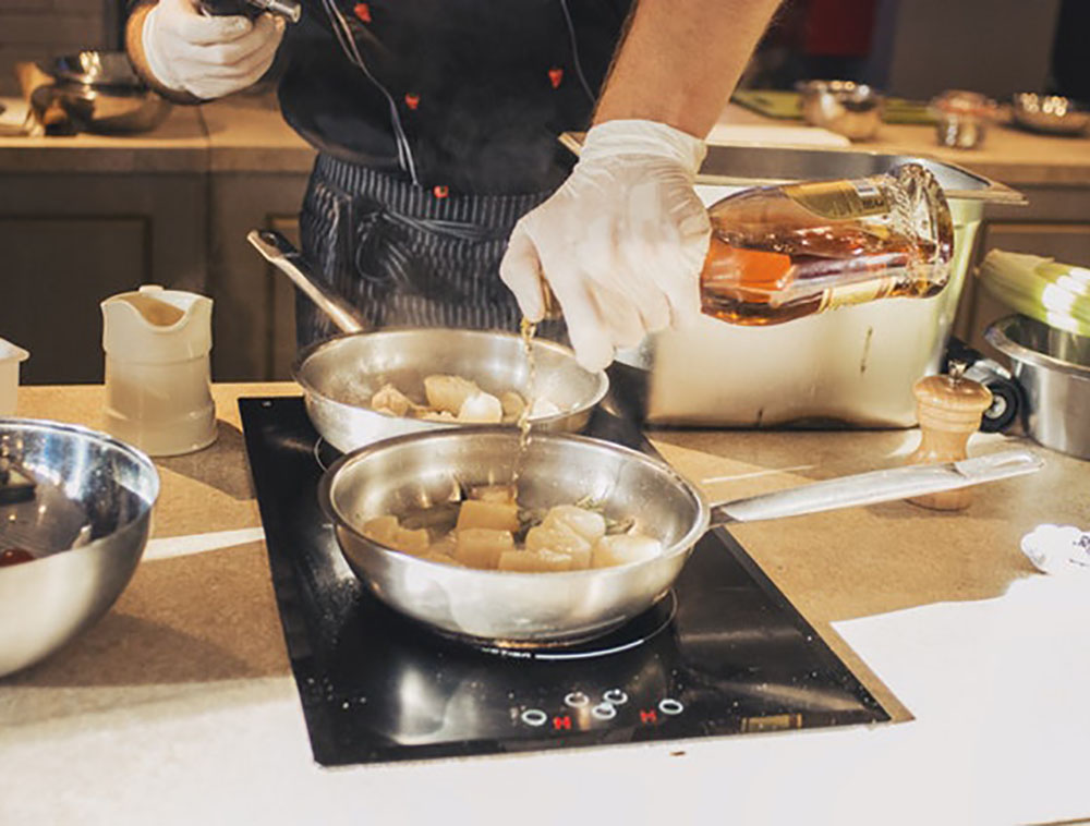 person with vinyl gloves holding oil bottle in front of stove