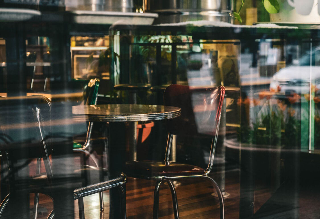 photo of chairs and tables of a restaurant taken at the window outside
