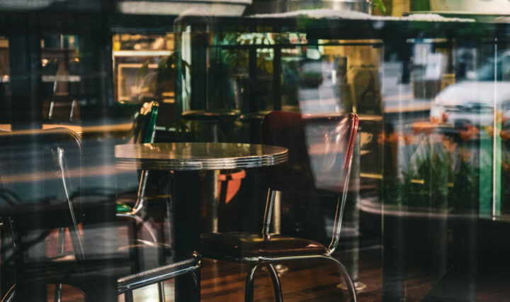 photo of chairs and tables of a restaurant taken at the window outside