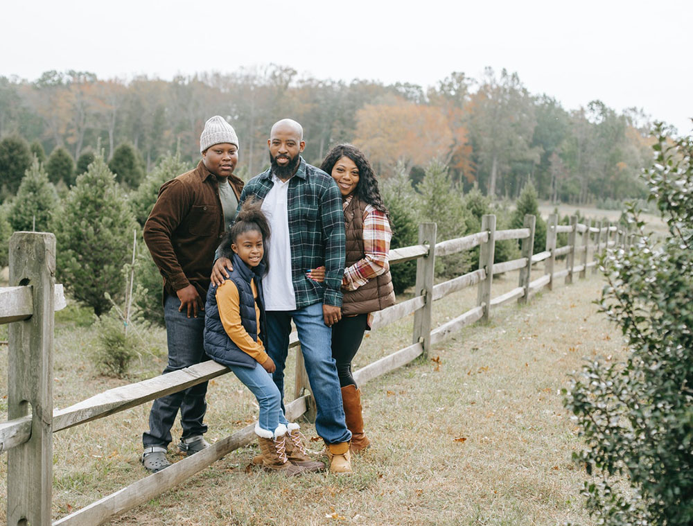 family of four embracing near fence in a countryside
