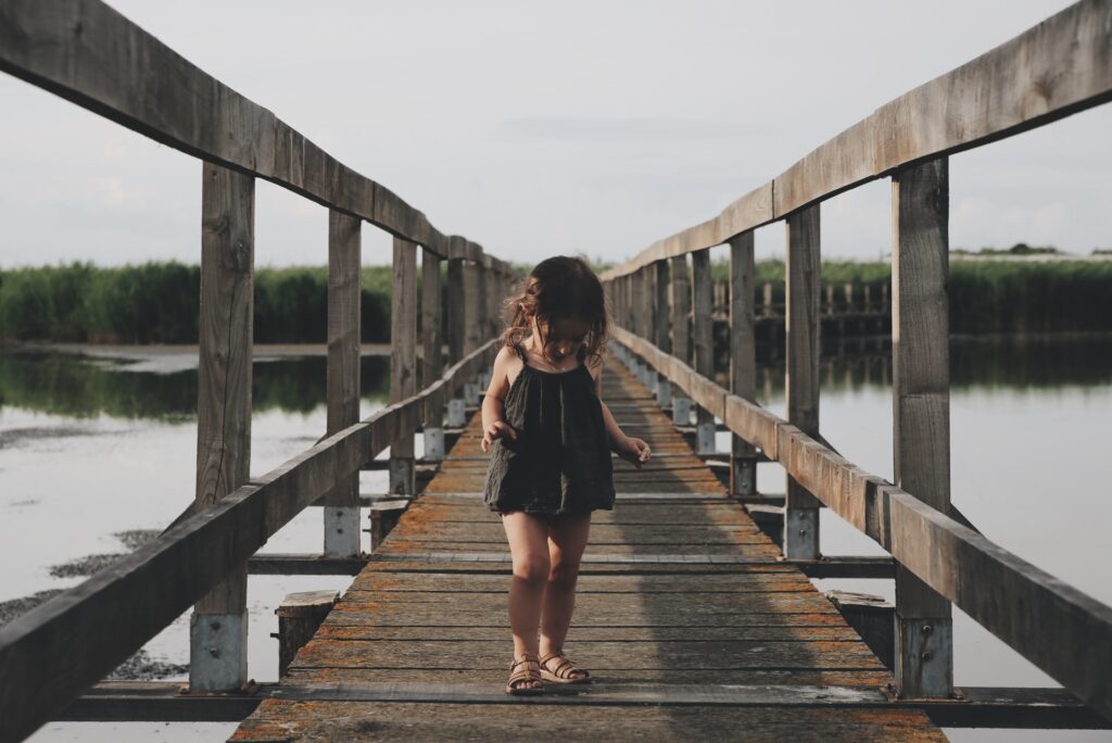small girl with black camisole walking on dock