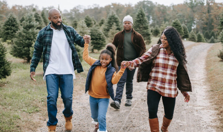 smiling family of four walking on tree farm road