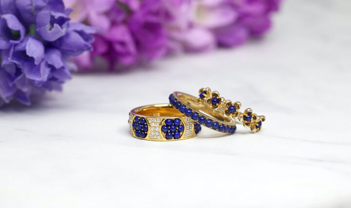 three gold-plated rings on a white table with blue crystals