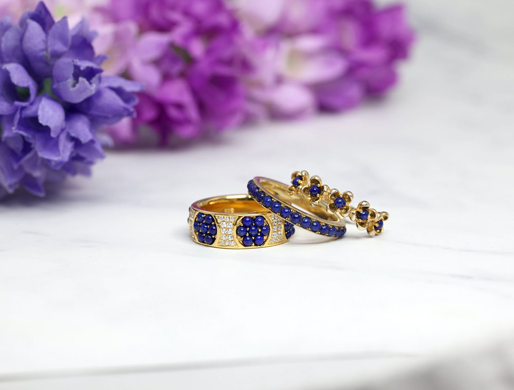three gold-plated rings on a white table with blue crystals