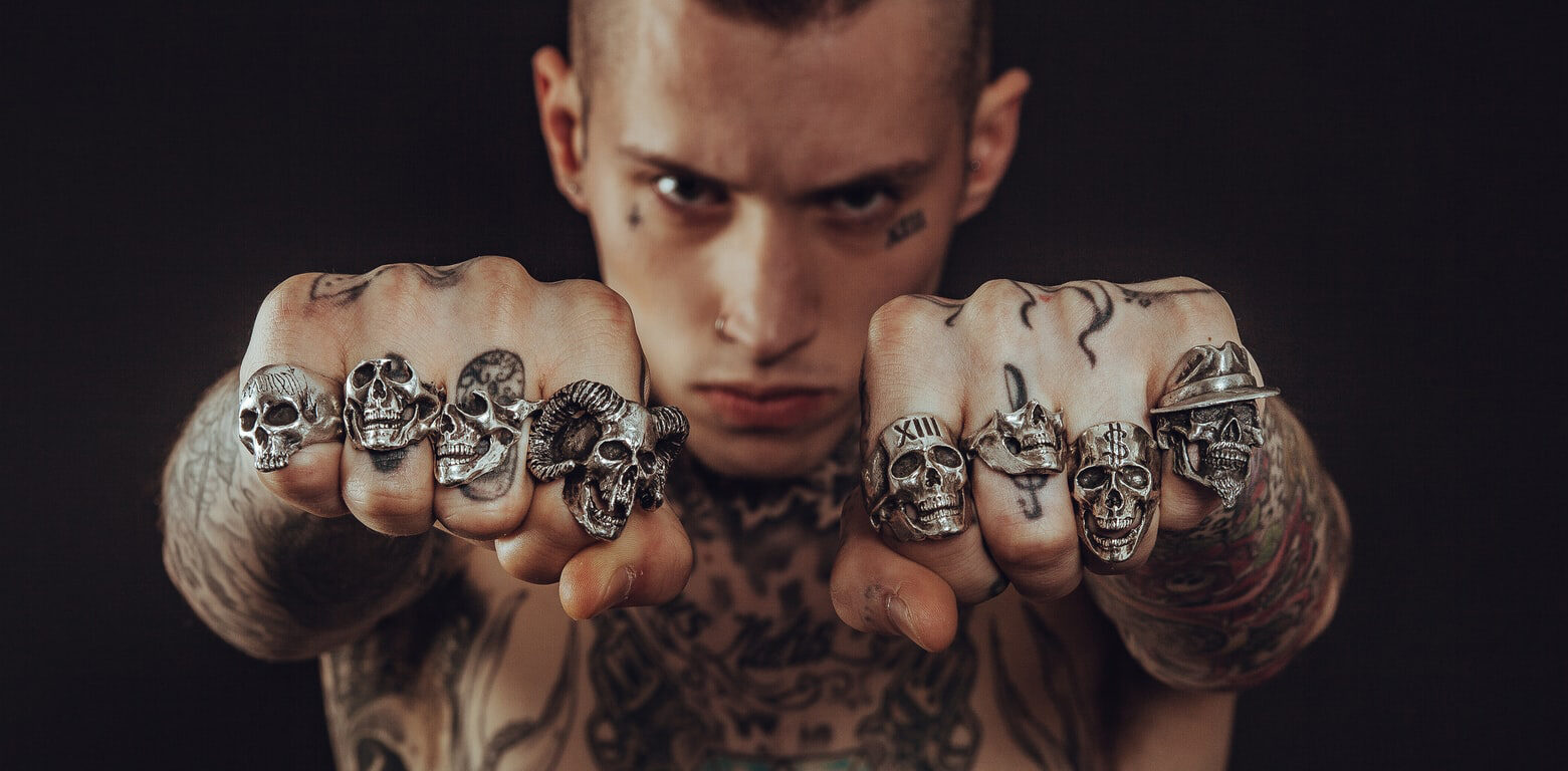 tattooed man showing off his biker rings on both hands