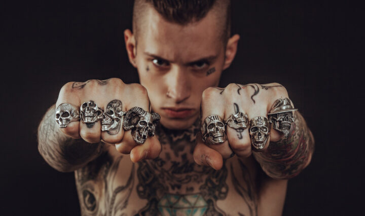 tattooed man showing off his biker rings on both hands