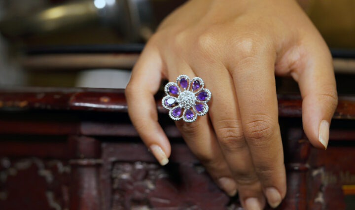 woman's hand on a furniture wearing a silver floral ring with amethyst stones