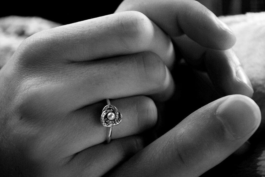 grayscale photo of a hand wearing a minimalist floral pearl silver ring